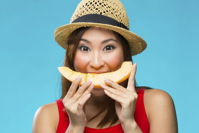 Happy Chinese Woman holding fruit on colorful background.