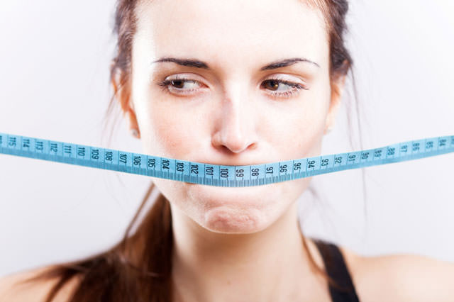 Woman with measuring tape on mouth