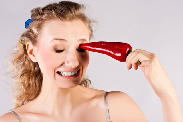 Beautiful woman teeth, eating red hot chili pepper