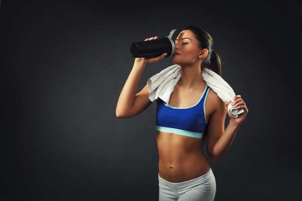 Attractive young woman drinking proteins